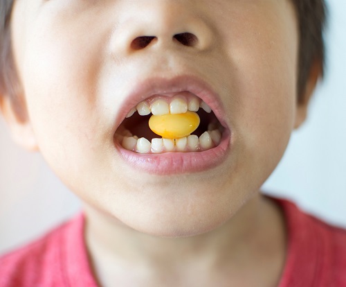 boy with yellow candy in between teeth
